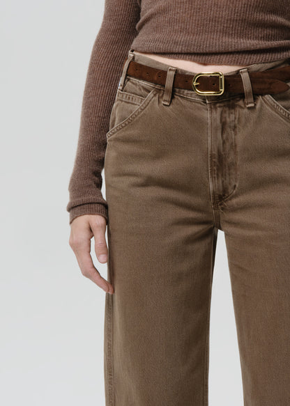 Person wearing brown pants and a matching sweater on a grey background