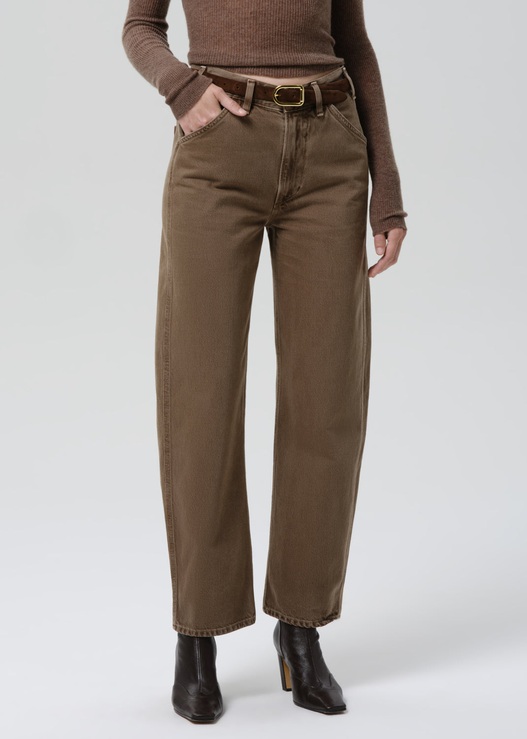 Person wearing brown pants and a brown top on a grey background