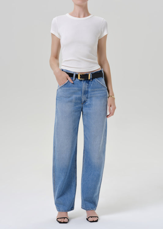 Person wearing a white t-shirt with blue pants on a grey background