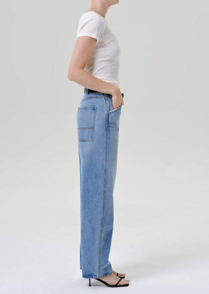 Person wearing a white t-shirt with blue pants on a grey background