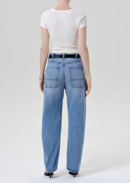 Person wearing a white t-shirt with blue pants on a grey background