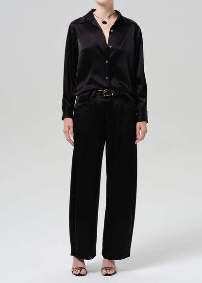 Person wearing a black satin button front blouse with black wide leg trousers on a grey background