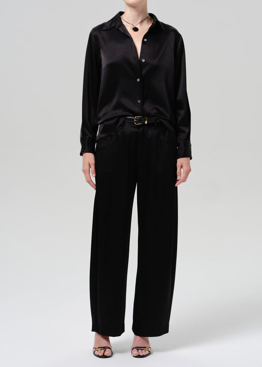 Person wearing a black satin button front blouse with black wide leg trousers on a grey background