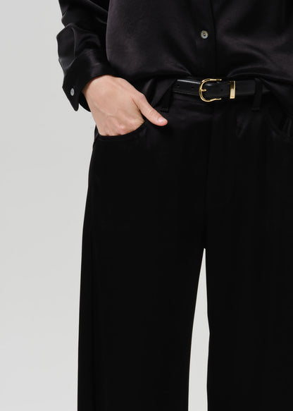 Close-up of black wide leg trousers on a grey background