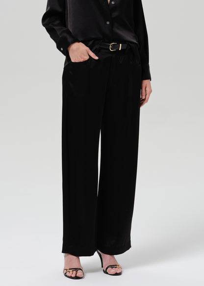 Person wearing a black satin button front blouse with black wide leg trousers on a grey background
