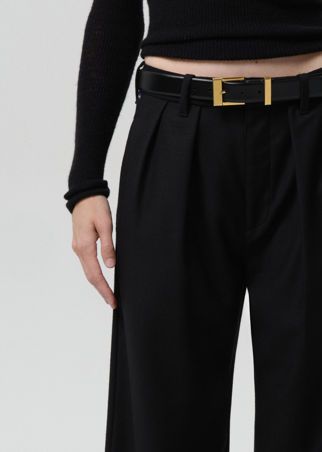 Close-up of black wide leg trousers on a grey background
