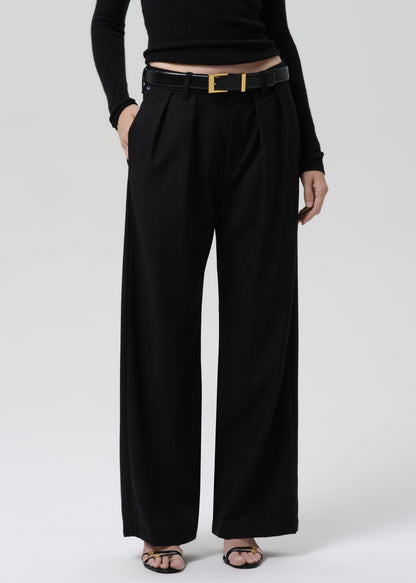 Person wearing a black fitted long sleeve sweater with black wide leg trousers on a grey background
