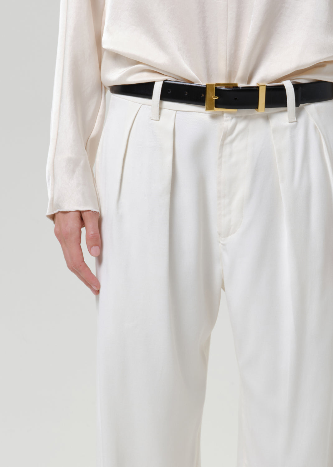 Close-up of white wide leg pants on a grey background.