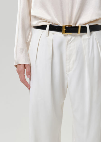 Close-up of white wide leg pants on a grey background.