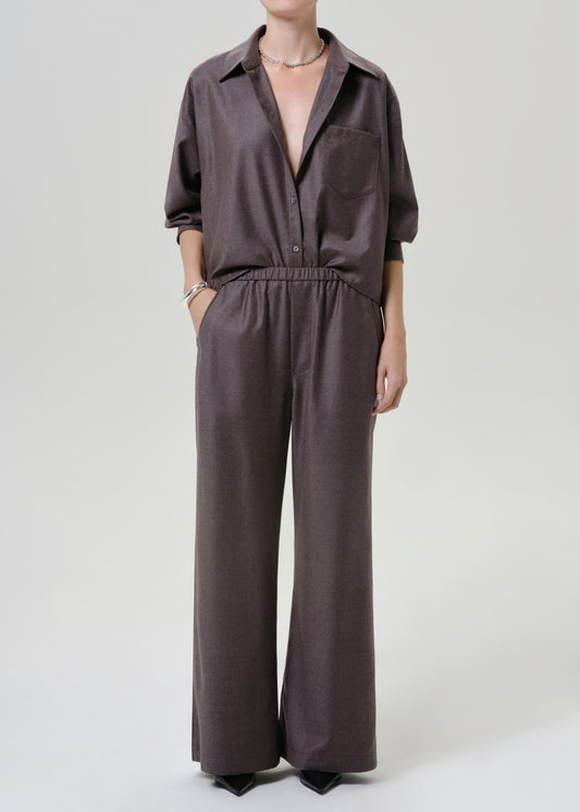 Woman wearing dark brown wide leg pants with a matching dark brown short sleeve top on a grey background.