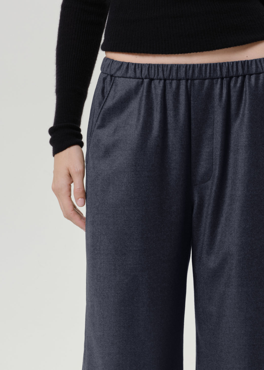 Close-up of dark grey wide leg pants on a grey background.