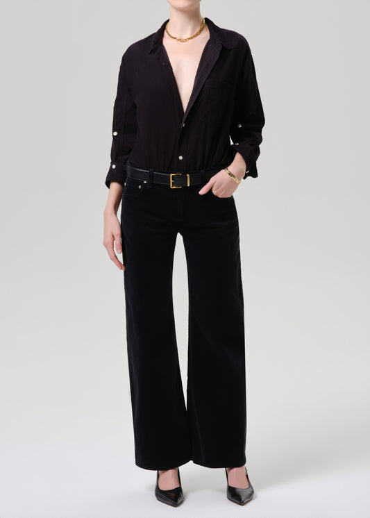 Person wearing a black outfit with a belt on a grey background