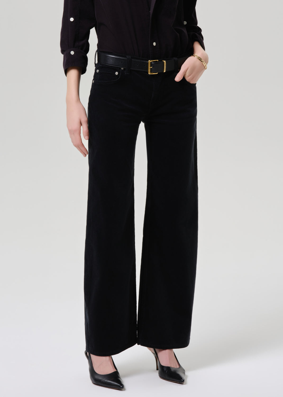 Person wearing black wide-leg pants with a grey background