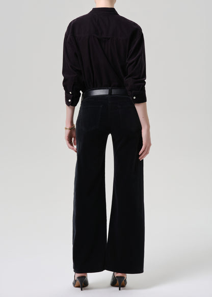 Person wearing a black outfit with wide-leg pants on a grey background