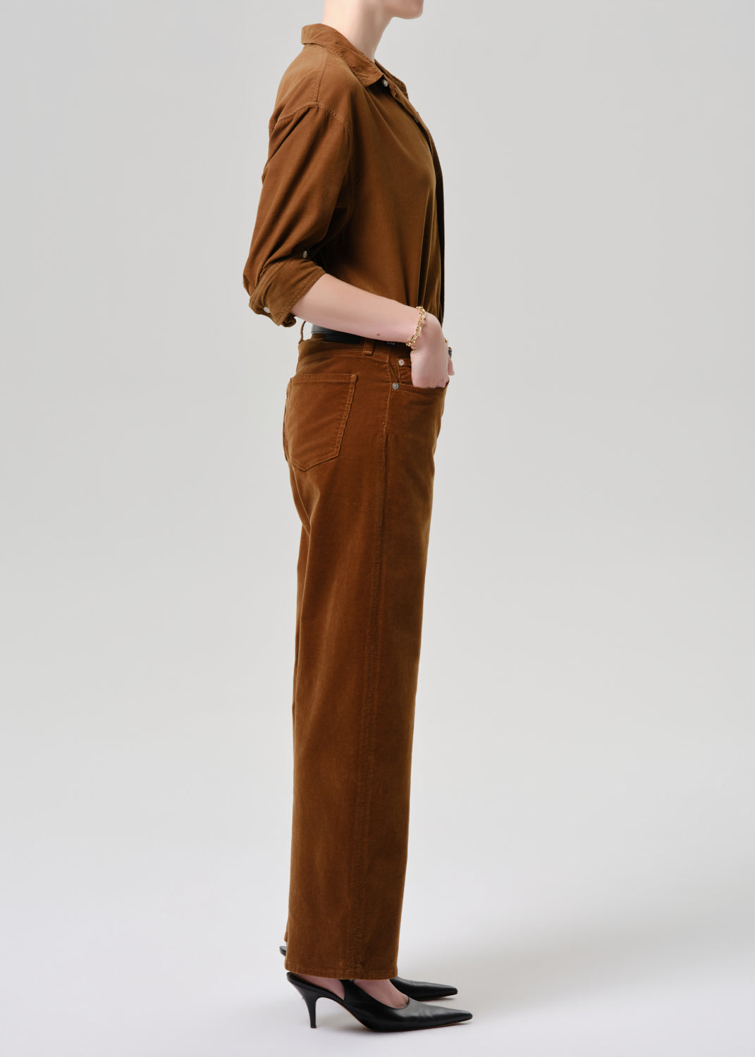 Person wearing a brown shirt and pants on a grey background