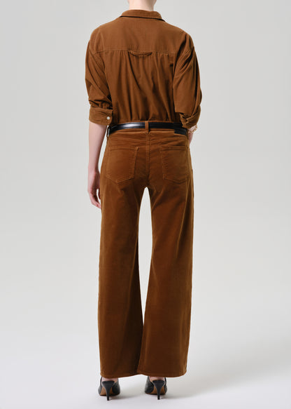 Person wearing a brown corduroy outfit on a grey background