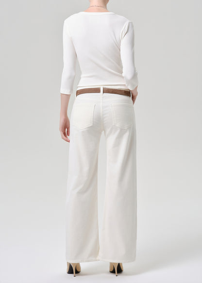 Person wearing a white outfit with wide-leg pants on a grey background
