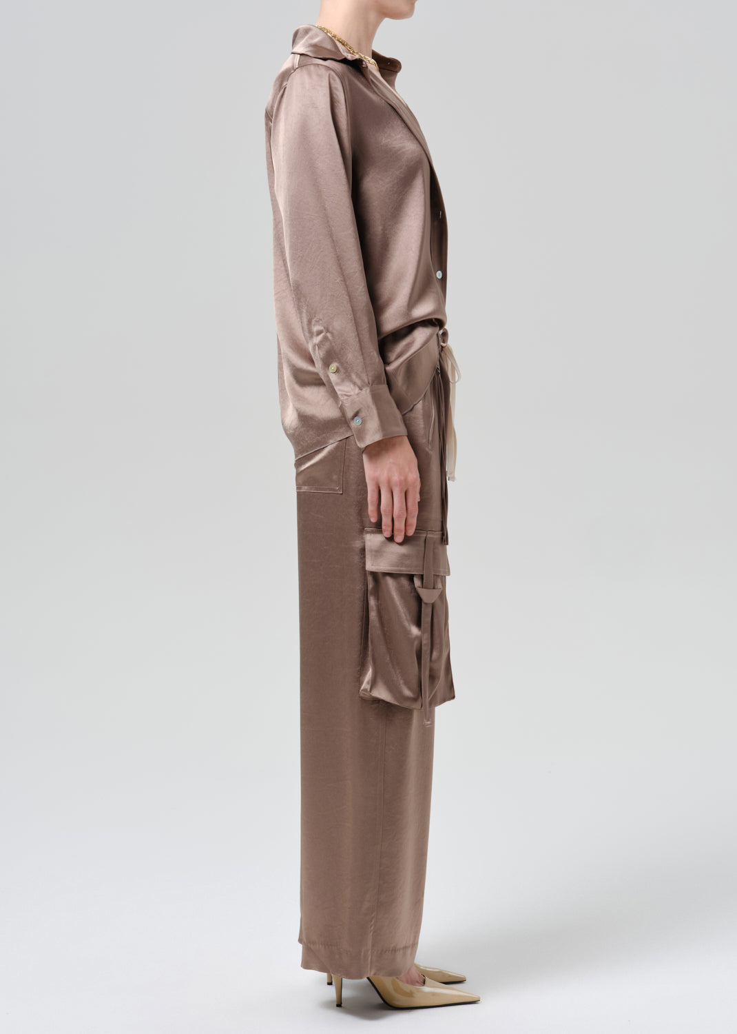 Person wearing silk brown shirt and pants on a grey background