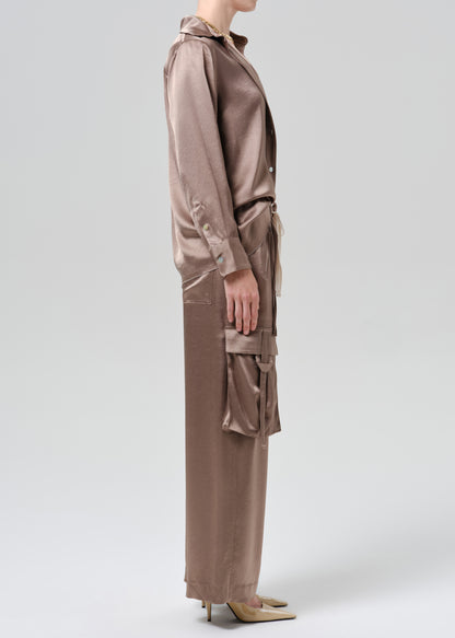 Person wearing silk brown shirt and pants on a grey background