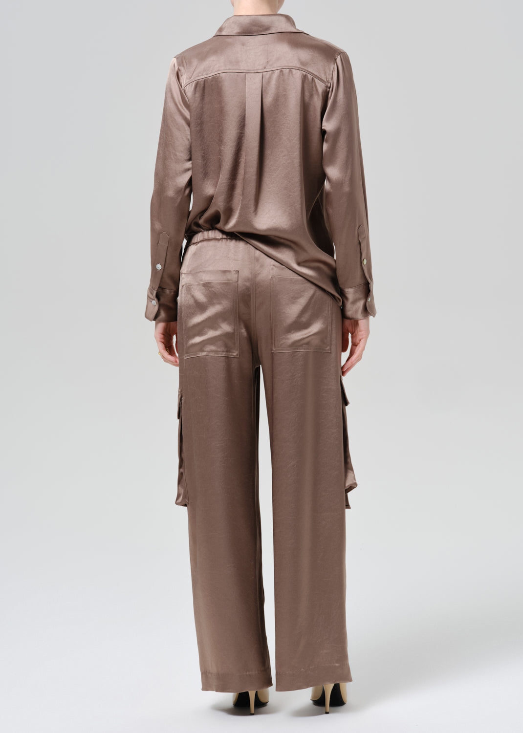 Person wearing silk brown shirt and pants on a grey background