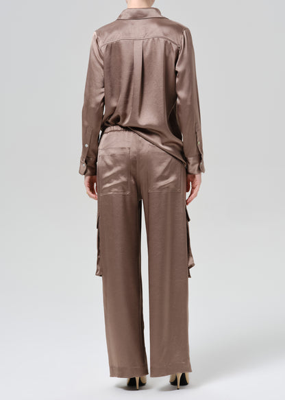 Person wearing silk brown shirt and pants on a grey background