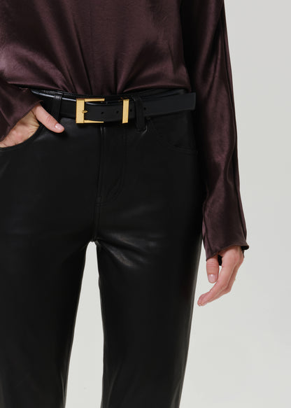 Close-up of black leather pants on a grey background.