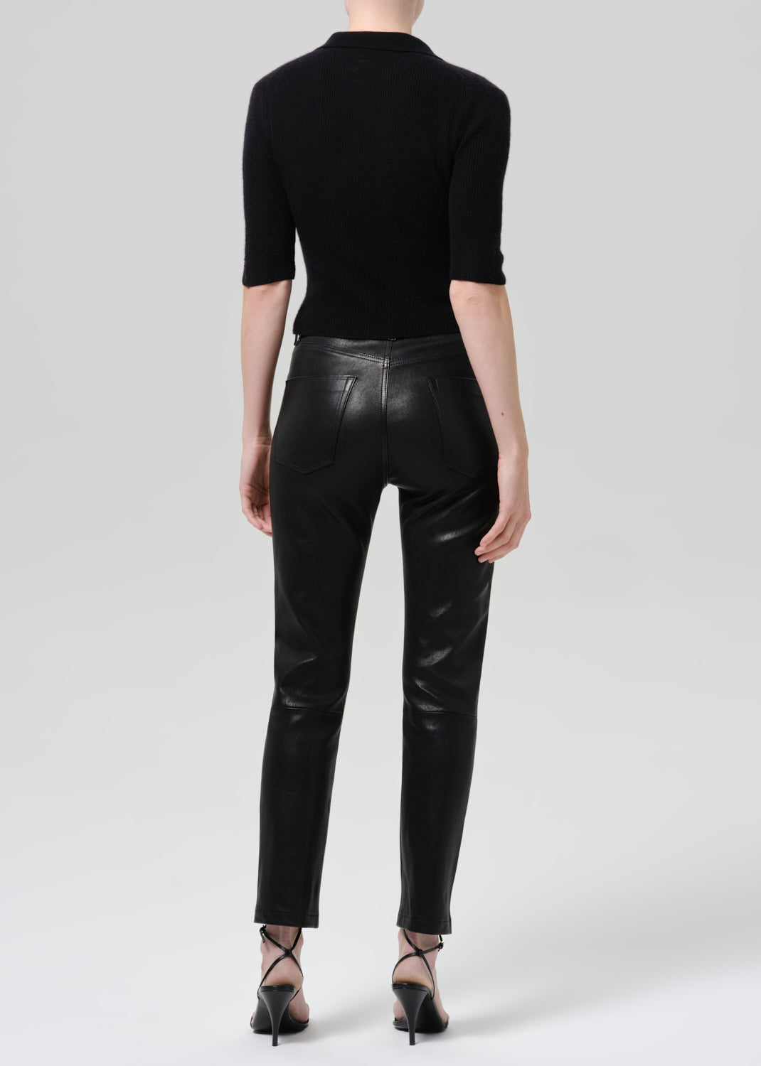 Person wearing black outfit on a grey background