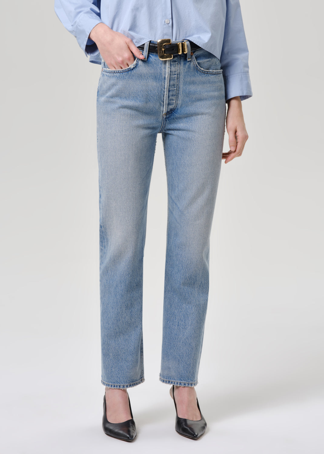 Person wearing light blue jeans and a light blue shirt on a grey background