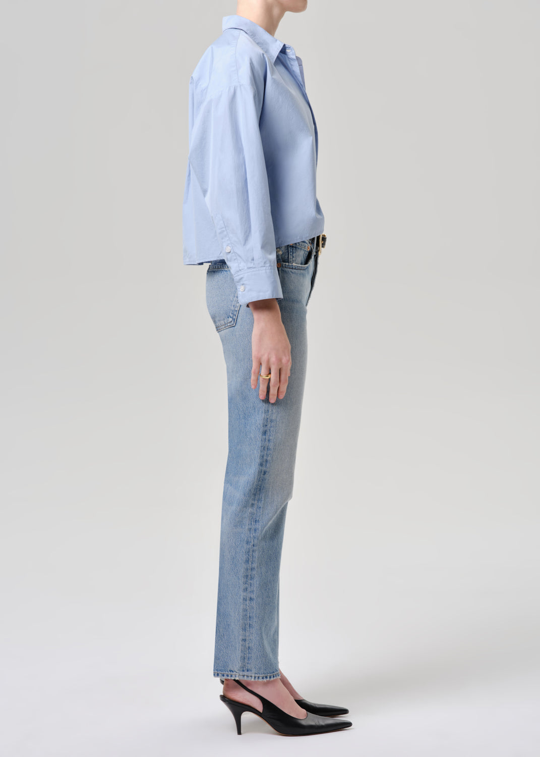 Person wearing a light blue shirt and jeans on a grey background