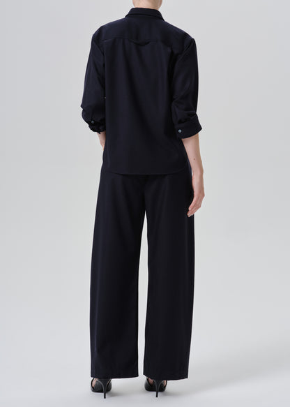 A model shown from the back wearing a dark navy blue shirt and wide-leg trousers set, paired with black heels, against a grey background.