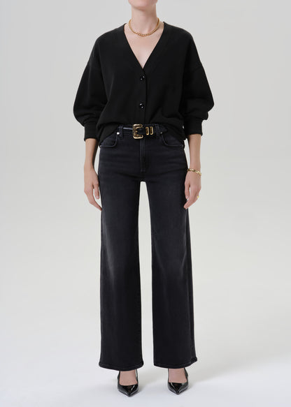 Person wearing a black cardigan and black pants on a grey background