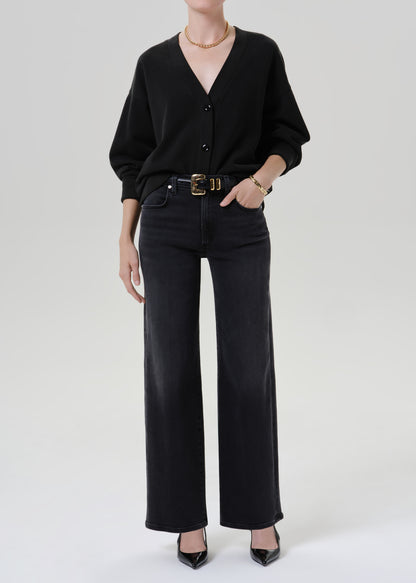 Person wearing black cardigan sweater with black pants on a grey background