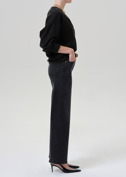 Person wearing black cardigan sweater with black pants on a grey background