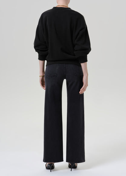 Person wearing black cardigan sweater with black pants on a grey background