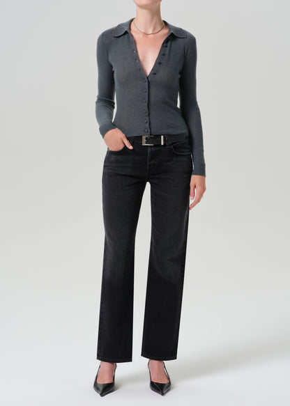 A model wearing a dark grey long-sleeve button-up knit top, black wide-leg jeans, and black pointed-toe heels, standing against a grey background.