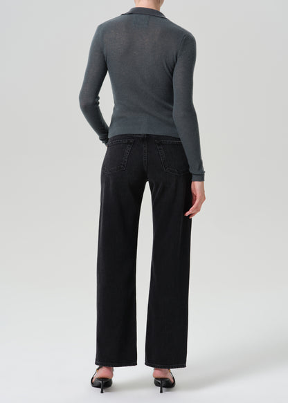 A model shown from the back wearing a dark grey long-sleeve knit top, black wide-leg jeans, and black pointed-toe heels against a grey background.