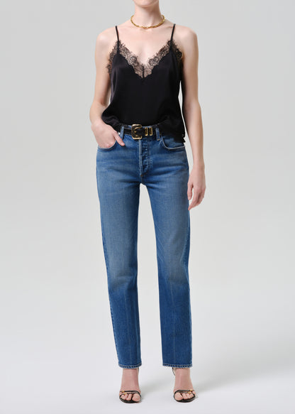 Person wearing a black lace top and blue jeans on a grey background