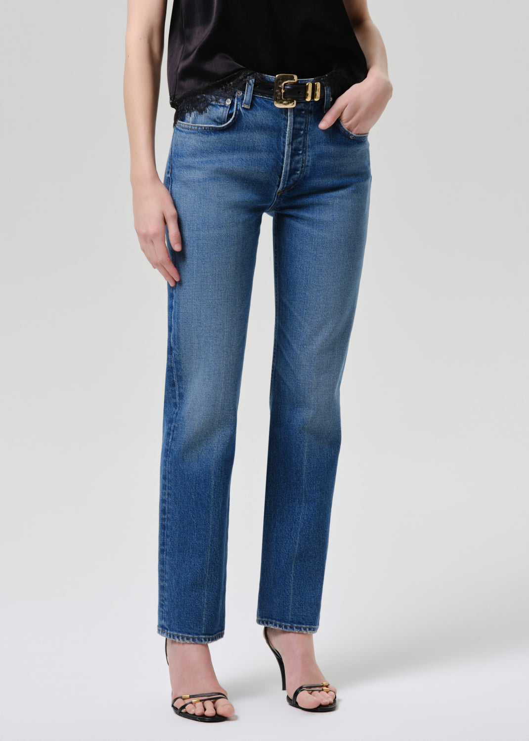 Person wearing blue jeans on a grey background