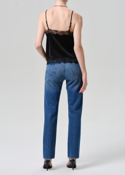 Person wearing a black lace top and blue jeans on a grey background