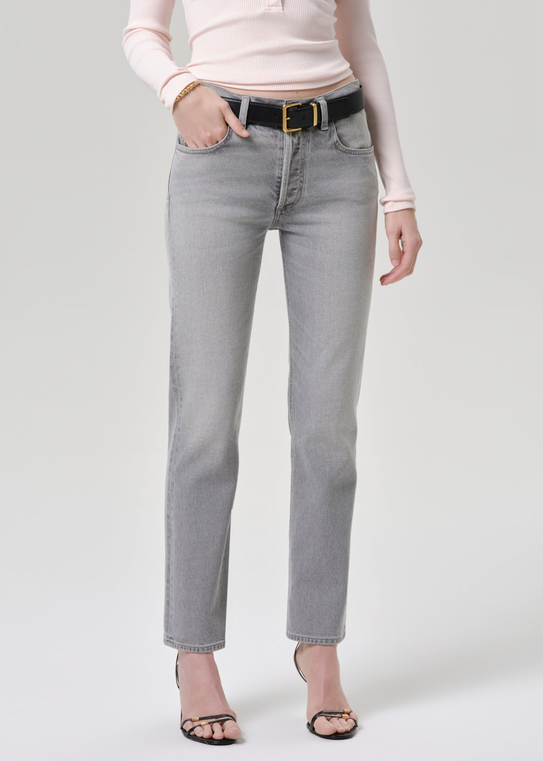 Person wearing light gray jeans with a grey background