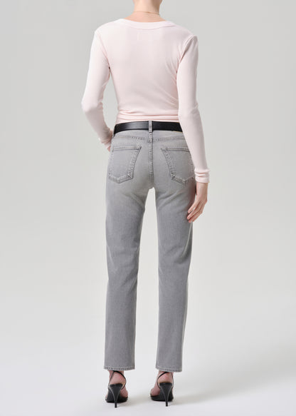 Person wearing gray jeans and a light pink long-sleeve top on a grey background