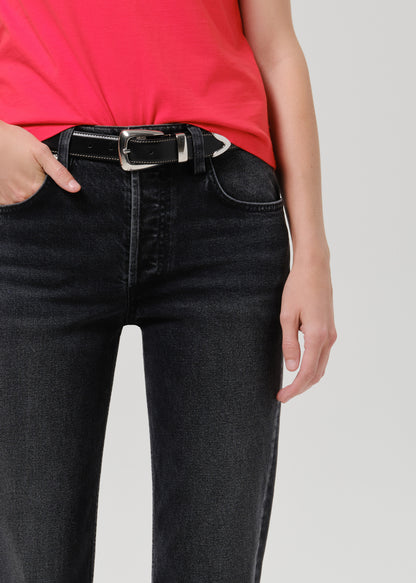 Person wearing a bright pink short sleeve crewneck tee with black denim jeans on a grey background