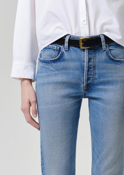 Person wearing blue jeans and a white shirt with a grey background
