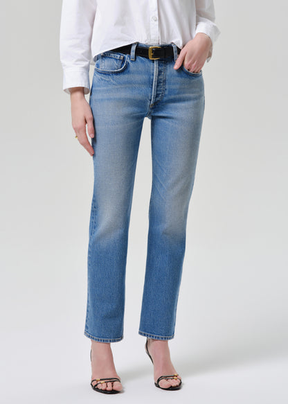 Person wearing blue jeans and a white shirt on a grey background