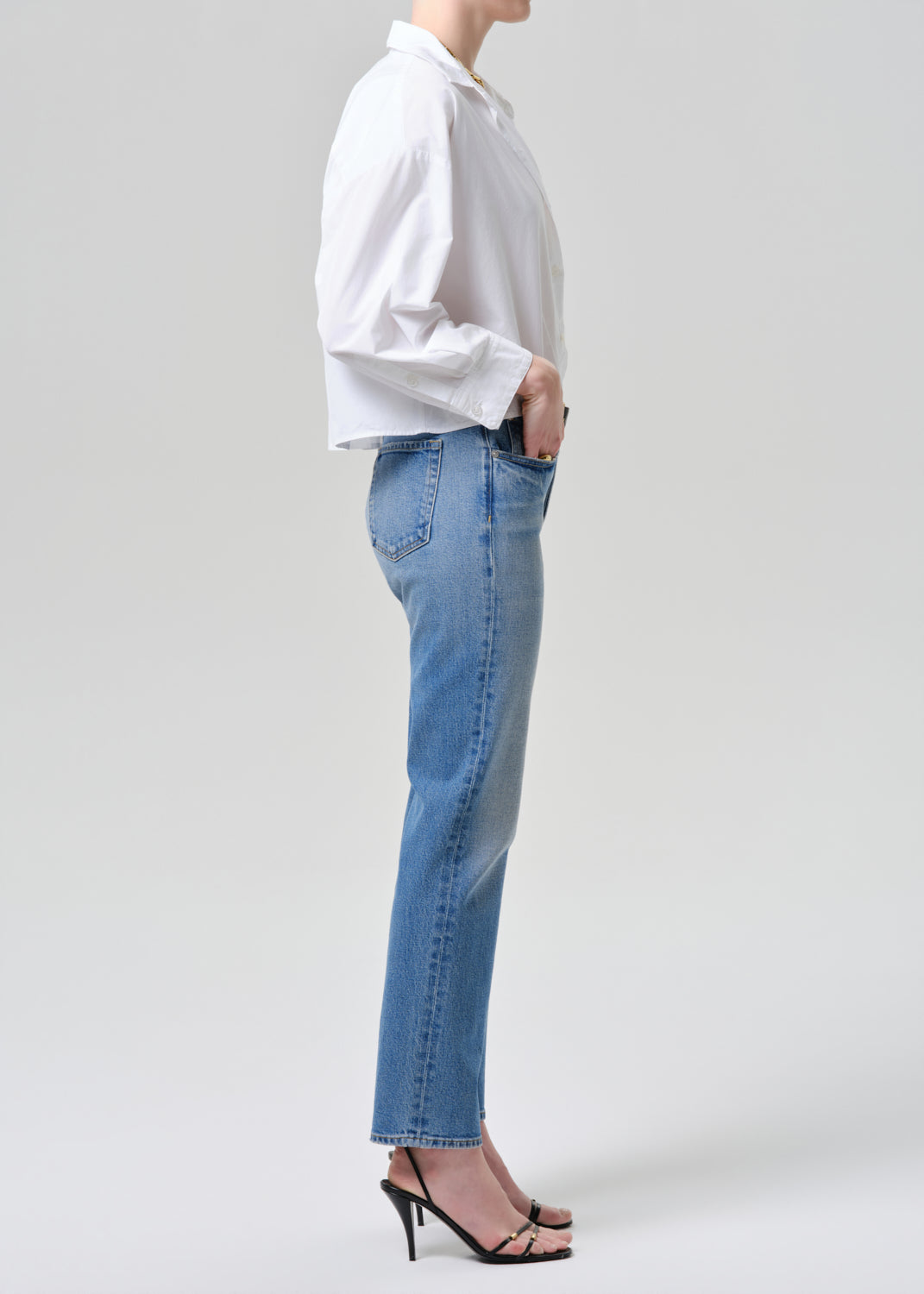Person wearing a white shirt and blue jeans on a grey background