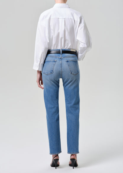 Person wearing blue jeans and a white shirt from behind on a grey background