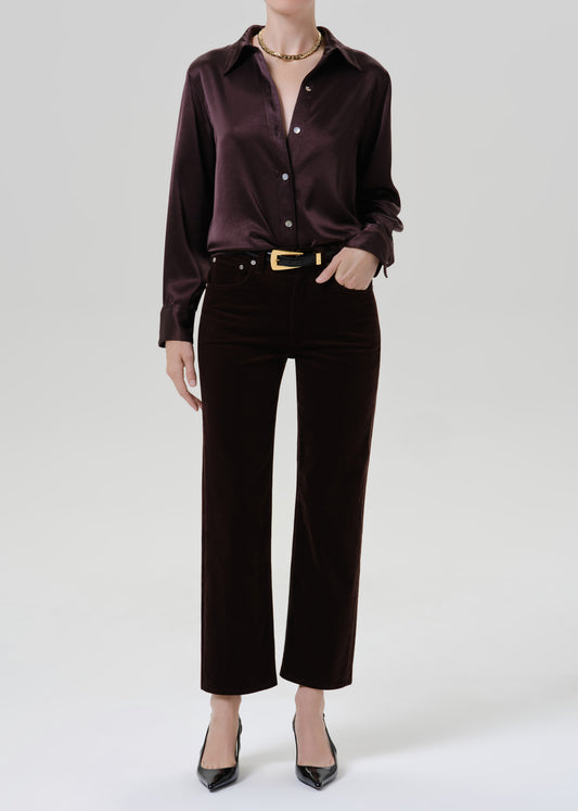 Person wearing burgundy button up shirt with black pants on a grey background