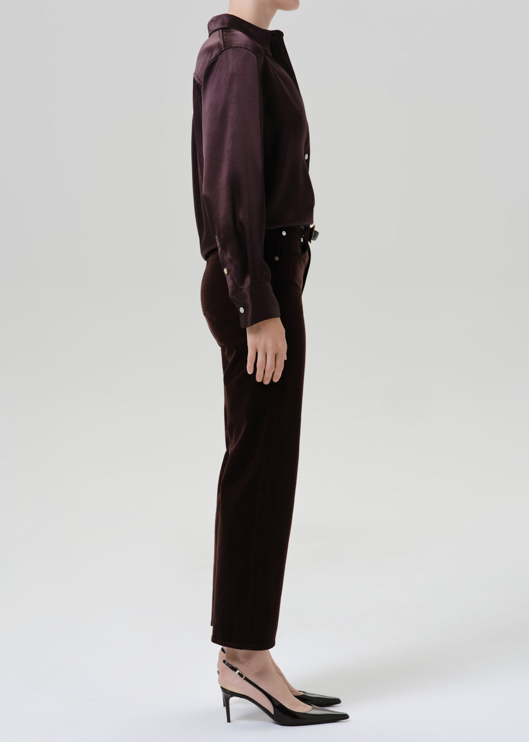 Person wearing burgundy button up shirt with black pants on a grey background