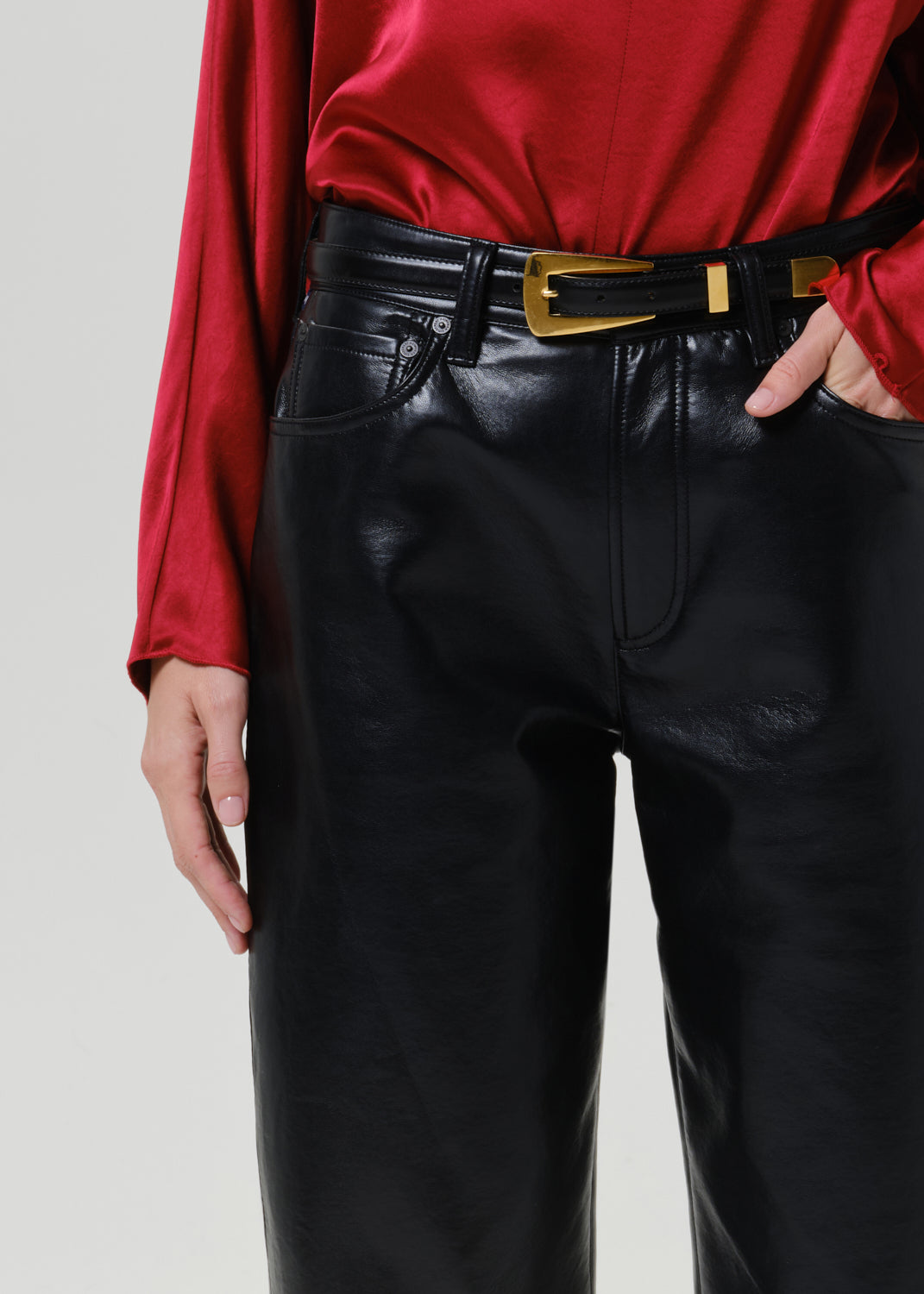 Close-up of black leather pants on a grey background.