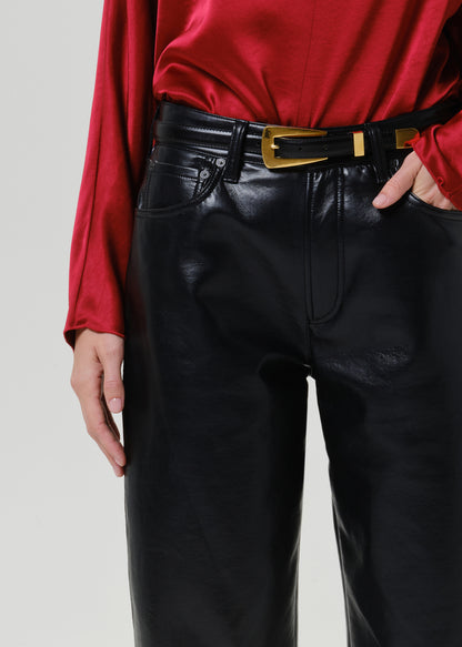 Close-up of black leather pants on a grey background.